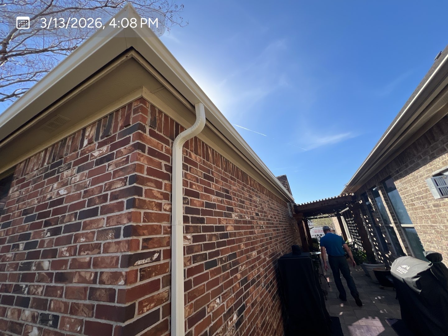 Completed gutter and downspout installation on the side of a brick home